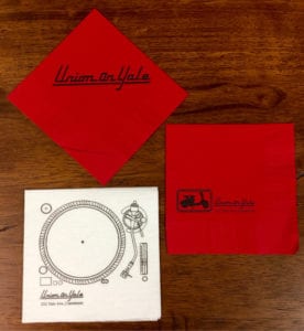 2 red and 1 white "Union on Yale" beverage napkins, showing the evolution of the logo