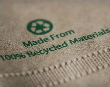 "Made from 100% Recycled Materials" green text with recycling emblem on kraft paper napkin