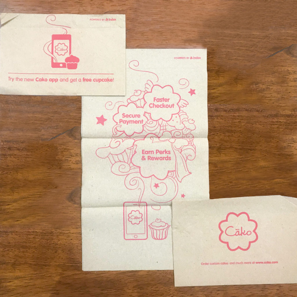 Kraft dispenser napkin with printing on front, back, and center panels reading, "try the new Cako app and get a free cupcake! Faster Checkout, Secure Payment, Earn Perks & Rewards."